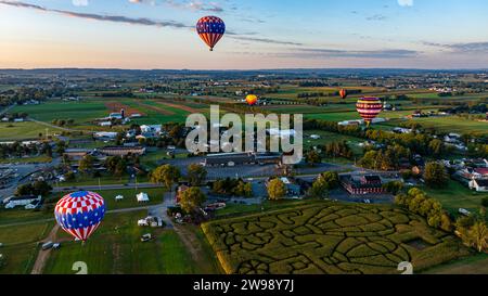 Vista aerea di numerose mongolfiere che partono e galleggiano sulla Pennsylvania rurale all'alba in una soleggiata mattinata d'estate Foto Stock