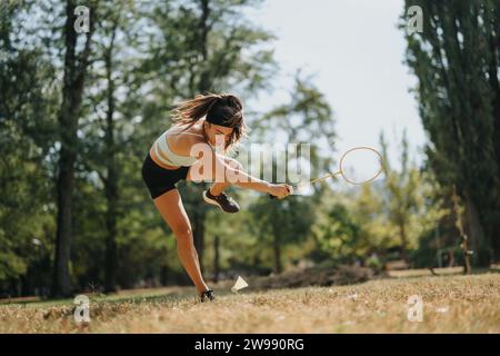 Una giocatrice di badminton che cade dopo un tentativo fallito di raggiungere e colpire lo shuttle con la racchetta. Foto Stock