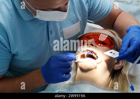 Il dentista esamina la condizione dei denti con l'aiuto di strumenti medici nella ragazza del paziente. Ricezione primaria. Clinica odontoiatrica. Assistenza sanitaria. Foto di alta qualità Foto Stock