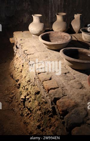 Una collezione di vasi in terracotta disposti in fila su uno sfondo sporco Foto Stock