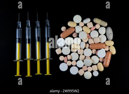 Vista dall'alto di siringhe e pillole su sfondo nero. Foto Stock