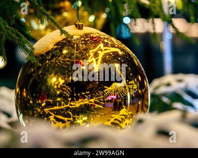 Un ornamento natalizio dorato appeso a un ramo d'albero Foto Stock
