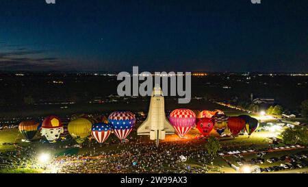 Una vista aerea delle mongolfiere che fanno un balloon blow notturno con uno stadio di canter in mongolfiera dello Space Shuttle, in una serata estiva Foto Stock