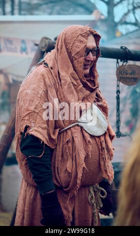 Un giovane adulto che indossa un grande cappotto con cappuccio si trova in un vivace ambiente all'aperto Foto Stock