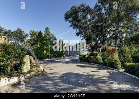 Grandi giardini di una casa di lusso con una fontana in un gazebo e una casa di guardia alla porta d'ingresso Foto Stock