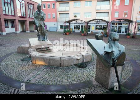 Edenkoben, Germania. 20 dicembre 2023. Le figure della fontana della Calza di Eterna si trovano in una piazza nel centro della città. Quando l'autore James Fenimore Cooper portò la sua calza di ferro alla vita letteraria nel 1823, combinò la storia selvaggiamente romantica con la critica alla civiltà e alla distruzione della natura. Il sentiero del ranger conduce alla Southern Wine Route? Crediti: Uwe Anspach/dpa/Alamy Live News Foto Stock