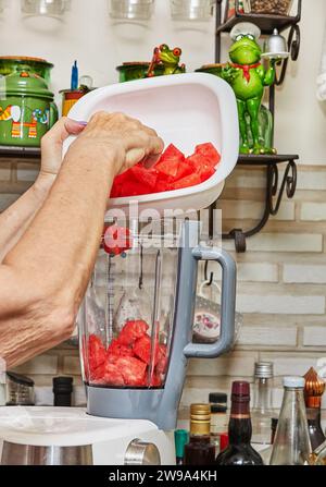 Chef esperto e professionale prepara sapientemente gazpacho delizioso in un frullatore in una moderna cucina casalinga, mettendo in mostra competenza e maestria culinaria. Foto Stock