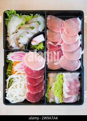 Fetta di pancia di maiale, gamberi, tagliatelle e fetta di calamari sul piatto, per sukoyaki, shabu shabu o coreani alla griglia Foto Stock