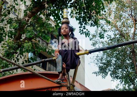 In uno spettacolo di strada o tamasha, una giovane ragazza indiana cammina un stretta, con l'aggiunta della difficoltà di bilanciare i vasi sulla testa; Mumbai, India Foto Stock