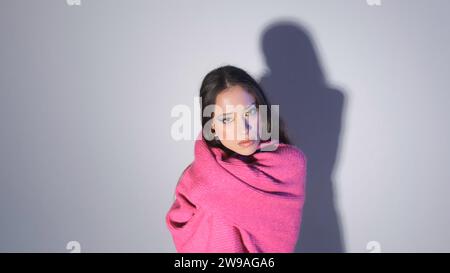 una ragazza con un maglione rosso posa su uno sfondo chiaro Foto Stock