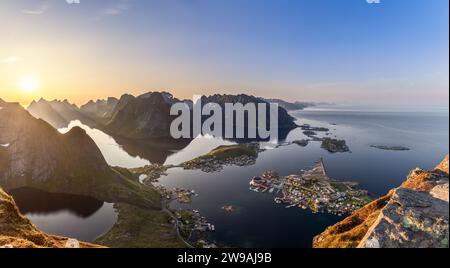 Il sole si stende in basso nell'ampio cielo su Reinebringen, offrendo un super panorama delle isole Lofoten. Vista del vibrante villaggio di pescatori di Reine in mezzo Foto Stock