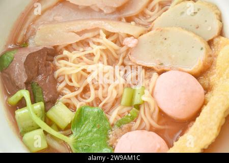 Spaghetti all'uovo gialli cinesi con palla di pesce e tritare il maiale in zuppa rossa su ciotola Foto Stock