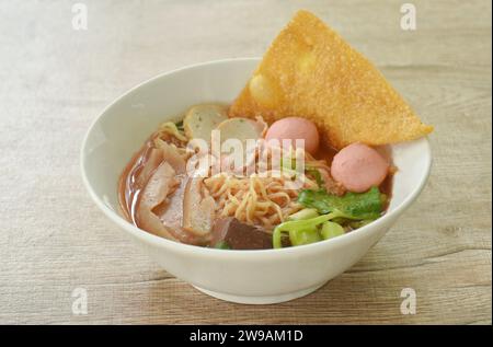 Spaghetti all'uovo gialli cinesi con palla di pesce e tritare il maiale in zuppa rossa su ciotola Foto Stock