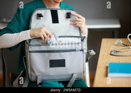 Infermiere medico che mette il distintivo in borsa quando lascia l'ospedale dopo il lavoro Foto Stock