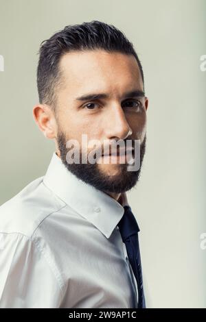 Uomo d'affari sicuro di sé con una barba ben curata si pone a semi-profilo Foto Stock