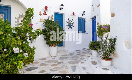 Bella isola greca. Una strada piena di bouganville fiorite sull'isola greca di Prodromos Paros. Tradizionali case imbiancate con porta blu Foto Stock