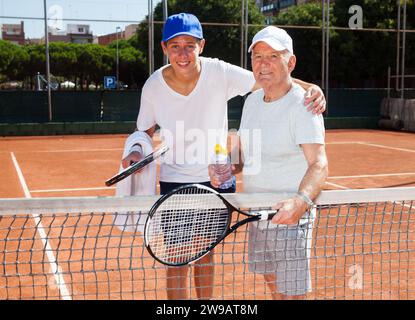 Nonno e nipote in posa sul campo da tennis Foto Stock