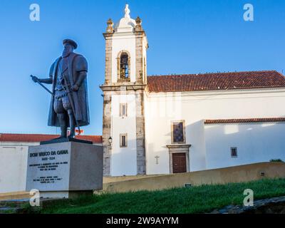 Statua di Dom Vasco da Gama con Igreja Matriz do Salvador de Sines chiesa cattolica nella città di Sines nella regione portoghese di Costa Azul Foto Stock