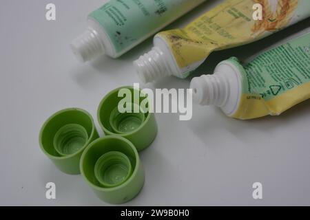 Cosmetici da donna, tre tubi di plastica usati di crema viso con tre cappucci verde chiaro disposti su uno sfondo di plastica bianca. Foto Stock