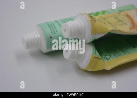 Cosmetici da donna, tre tubi di plastica usati di crema viso con tre cappucci verde chiaro disposti su uno sfondo di plastica bianca. Foto Stock