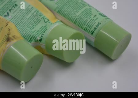 Cosmetici da donna, tre tubi di plastica usati di crema viso con tre cappucci verde chiaro disposti su uno sfondo di plastica bianca. Foto Stock