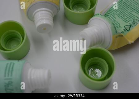 Cosmetici da donna, tre tubi di plastica usati di crema viso con tre cappucci verde chiaro disposti su uno sfondo di plastica bianca. Foto Stock