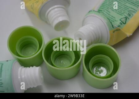 Cosmetici da donna, tre tubi di plastica usati di crema viso con tre cappucci verde chiaro disposti su uno sfondo di plastica bianca. Foto Stock