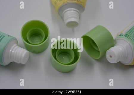 Cosmetici da donna, tre tubi di plastica usati di crema viso con tre cappucci verde chiaro disposti su uno sfondo di plastica bianca. Foto Stock