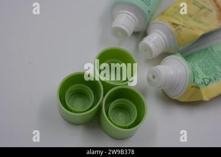 Cosmetici da donna, tre tubi di plastica usati di crema viso con tre cappucci verde chiaro disposti su uno sfondo di plastica bianca. Foto Stock