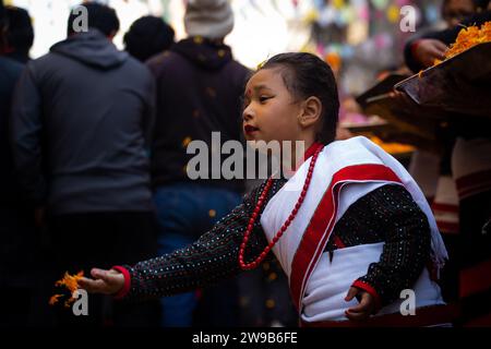 Kathmandu, Nepal. 26 dicembre 2023. Il 26 dicembre 2023, a Kathmandu, Nepal. Un bambino della comunità Newar in abbigliamento culturale ha spremuto petali di fiori come benvenuto durante la processione ralley 'Yomari Punhi'. (Foto di Abhishek Maharjan/Sipa USA) credito: SIPA USA/Alamy Live News Foto Stock