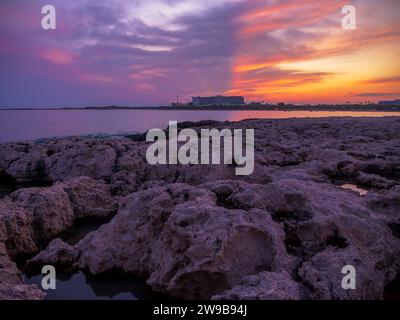 Vista dall'aspra costa rocciosa su un cantiere edile con l'hotel e gru sulla riva del Mar Mediterraneo in serata con colori incredibili Foto Stock