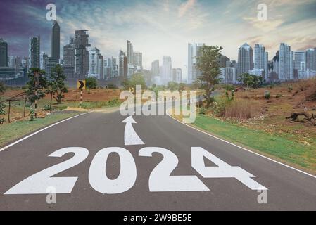 Concetto di Capodanno 2024. Testo 2024 scritto sulla strada in mezzo alla strada al tramonto. Inizio anno nuovo Foto Stock