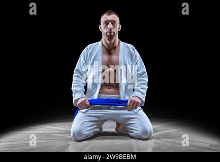 L'atleta professionista siede in palestra in un kimono con una cintura blu. Concetto di karate, jiu-jitsu, sambo, judo. Supporti misti Foto Stock