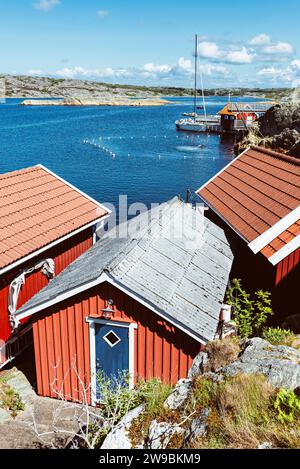 Tradizionali capanne rosse svedesi di fronte al bagno di Stocken, nell'arcipelago della costa occidentale della Svezia, sotto il sole estivo Foto Stock