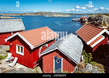 Tradizionali capanne rosse svedesi di fronte al bagno di Stocken, nell'arcipelago della costa occidentale della Svezia, sotto il sole estivo Foto Stock