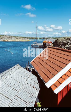 Tradizionali capanne rosse svedesi di fronte al bagno di Stocken, nell'arcipelago della costa occidentale della Svezia, sotto il sole estivo Foto Stock