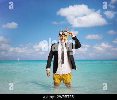 Uomo d'affari in mare con pantaloncini da bagno e tuta con cravatta Foto Stock