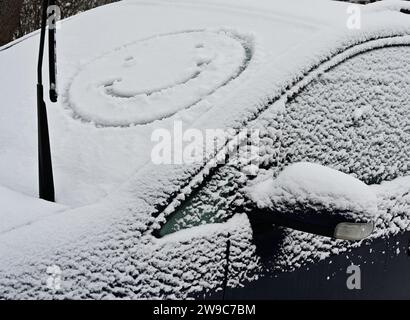 Un'auto invernale sorride felicemente mentre batte le temperature gelide, ricoperta da una coperta di neve, mentre è circondata dalla bellezza serena di t Foto Stock