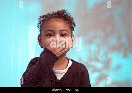 Una giovane ragazza afro-americana che tiene la mano sulla bocca mentre risveglia di fronte alla telecamera Foto Stock