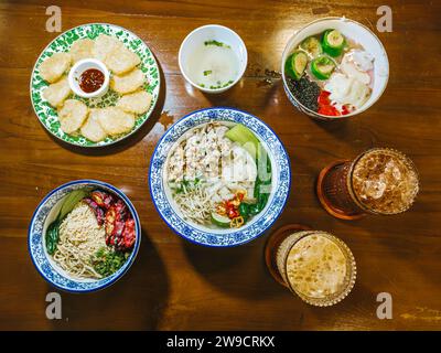 Un menu' di mix di piatti o piatti indonesiani e cinesi. Kwetiau, Noodles, es Campur, Cireng e bicchieri da caffè sul tavolo di legno. Foto Stock