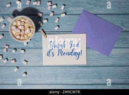 GRAZIE A DIO È LUNEDÌ Concept busta viola con tazza di caffè bianco e marshmallow su sfondo di legno. Il giorno più deprimente dell'anno di gennaio. Giorno commettere suicidio e depressione segno di motivazione. Vista dall'alto, base piatta Foto Stock