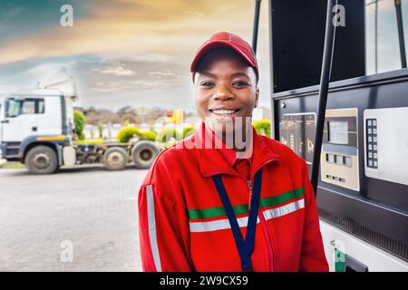 addetto afro-americano al rifornimento di auto alla stazione di servizio, camion in background Foto Stock