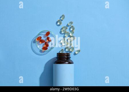 Una bottiglia di medicina con etichetta bianca per testo, pillole di vitamina e sparse, capsule di olio di pesce in una piastra di Petri su sfondo verde. Scena per gli spot Foto Stock