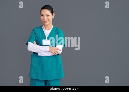 Ritratto in studio dell'infermiera riabilitativa in uniforme verde con le braccia incrociate Foto Stock