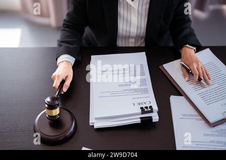 Avvocato donna d'affari che tiene HAMMER in uno studio legale mentre legge la causa e controlla il documento di affari finanziario per analizzare la legislazione agr Foto Stock