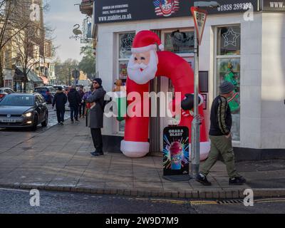 Scena di strada natalizia, con Babbo Natale gonfiabile, nella città di Market Harborough, Leicestershire. Foto Stock
