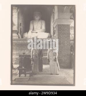 Un uomo e una donna con oggetti sulla testa e un bambino di fronte a una statua di Buddha, Myanmar, 1907 fotografa Myanmar, supporto fotografico stampa in argento gelatina Foto Stock