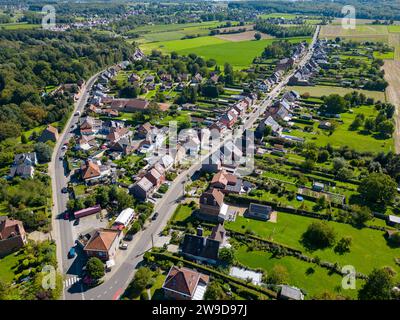 Lembeek, Halle, Vlaams Brabant, Belgio, 5 settembre 2023, questa fotografia aerea mostra l'affascinante villaggio di Lembeek, situato a Halle, Vlaams Brabant, Belgio. L'immagine cattura la diffusione lineare di case e strade che definiscono la struttura del villaggio, circondato dal verde lussureggiante della campagna belga. L'interazione dell'architettura residenziale con il paesaggio naturale illustra l'armoniosa miscela di elementi urbani e rurali. Vista aerea del villaggio di Lembeek a Halle. Foto di alta qualità Foto Stock