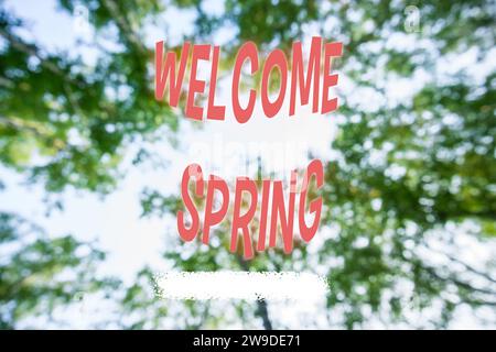 Sfondo sfocato verde con testo bianco primavera di benvenuto. Messa a fuoco selettiva Foto Stock