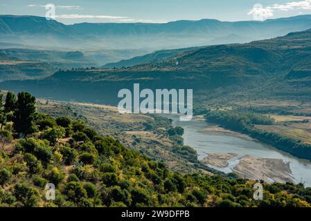 Un ampio fiume si snoda attraverso una valle nel Lesotho verso le montagne Foto Stock